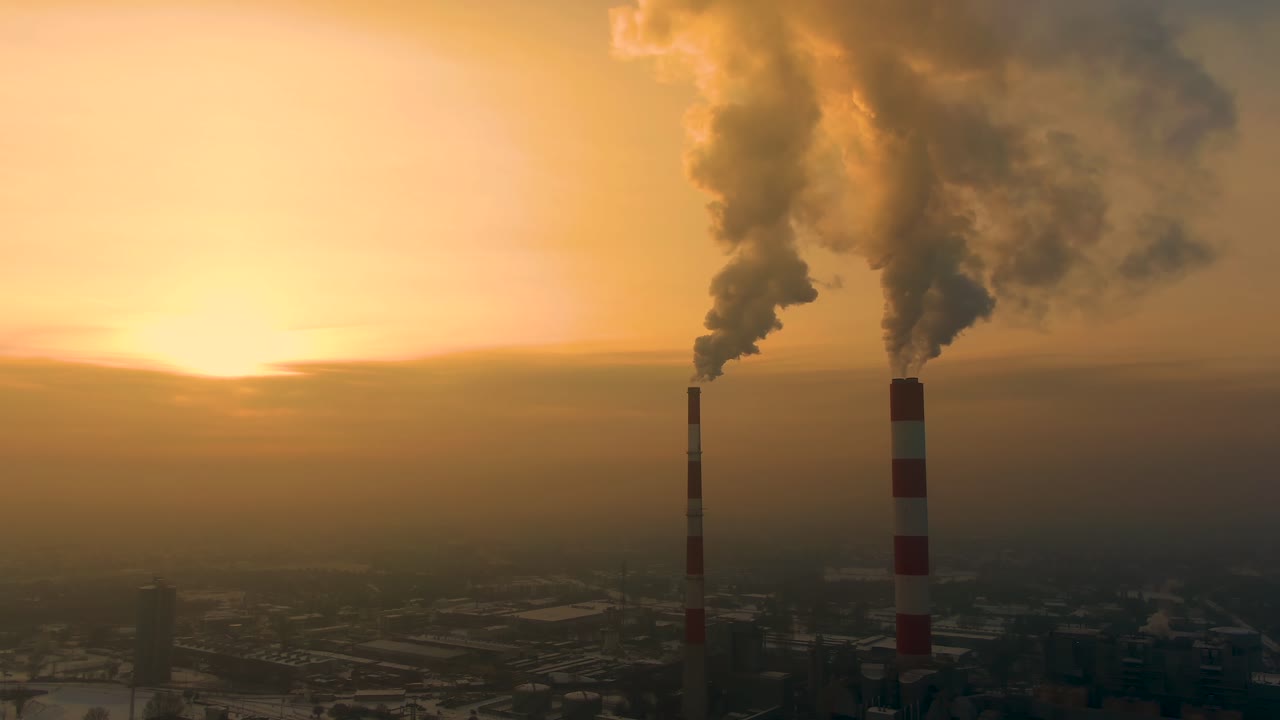 Power Plant emissions seen above the city during sunrise. Environmental pollution. Factory pipe polluting air.Panorama sunset. Smoking pipes Aerial view,