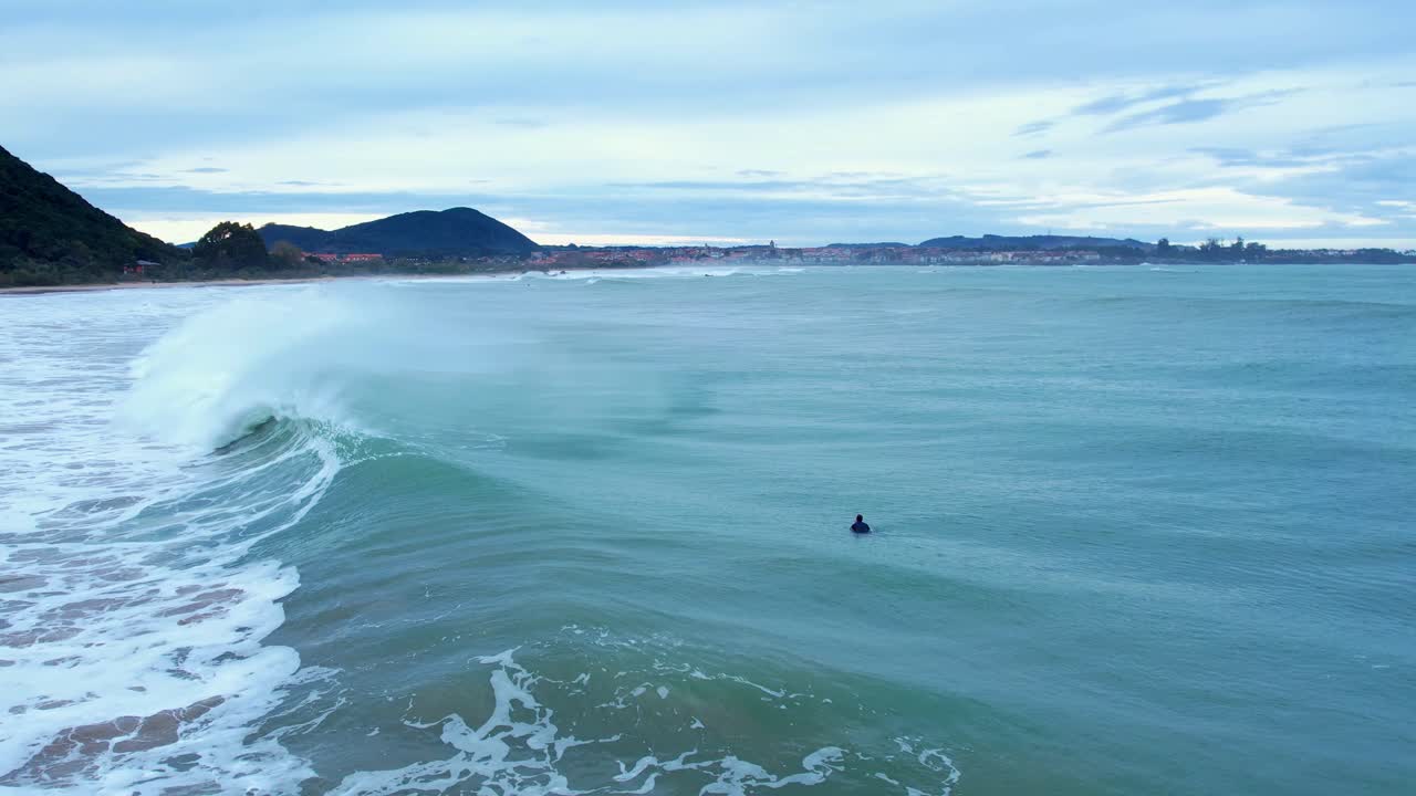 tiro de dron de un surfista saltando una ola en la playa