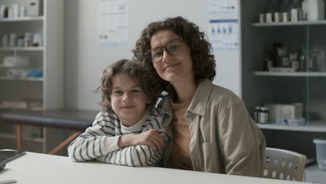 portrait of happy mother and little son sitting together in pediatric clinic