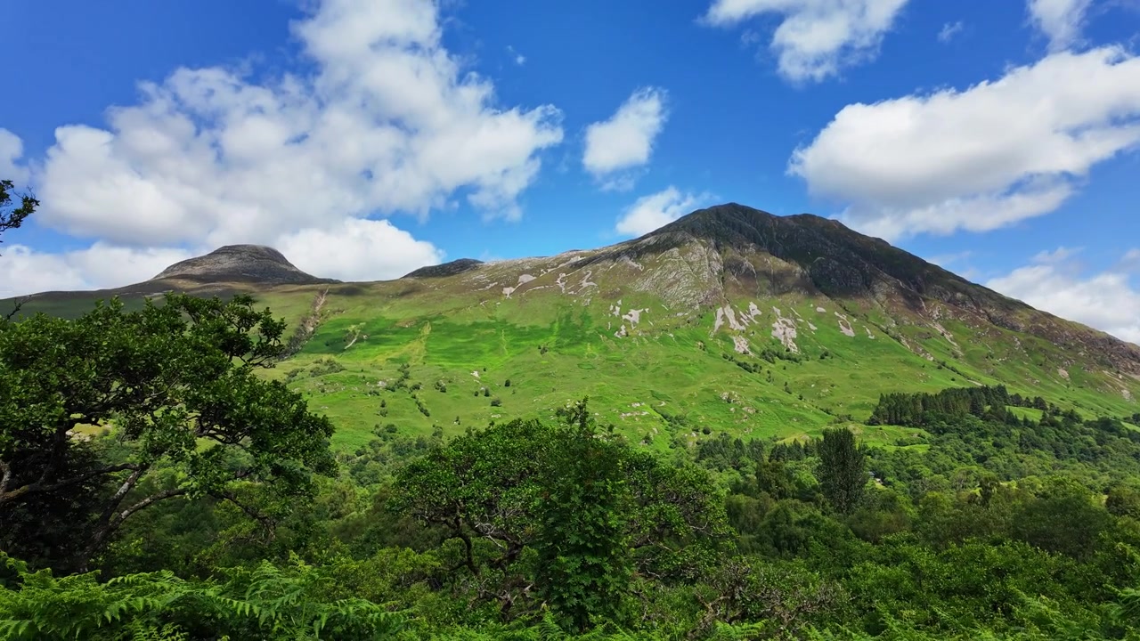 Panoramica mozzafiato di una vasta e verde valle nelle Highlands di Glencoe, Scozia, in una splendida giornata estiva.