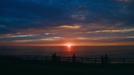 group of people enjoying beautiful romantic sunset view over the sea at perran sands beach in perranporth, cornwall, england, uk. - timelapse