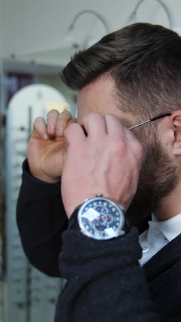 man trying on eyeglasses in an optical shop