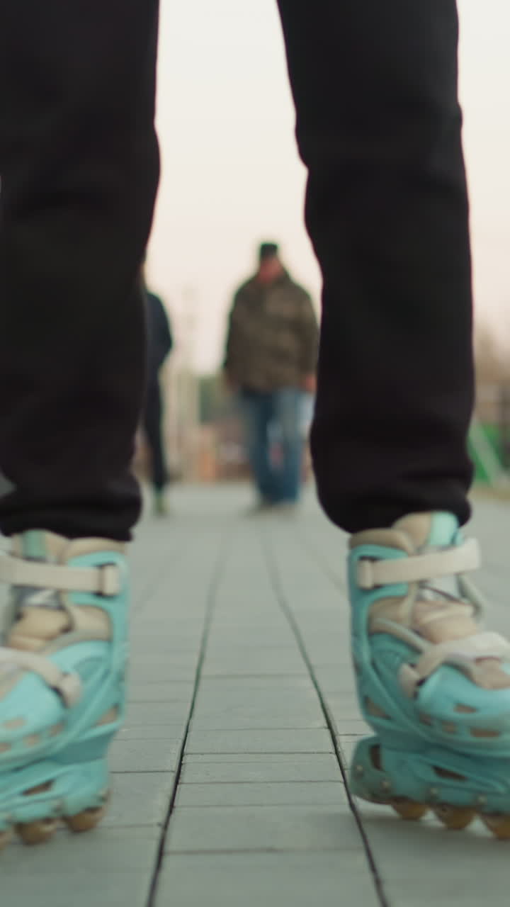 una mujer está patinando a lo largo de un camino pavimentado en un parque, con una chaqueta de melocotón y pantalones negros. el fondo revela una escena animada con otros visitantes del parque, incluido un niño en una bicicleta y personas