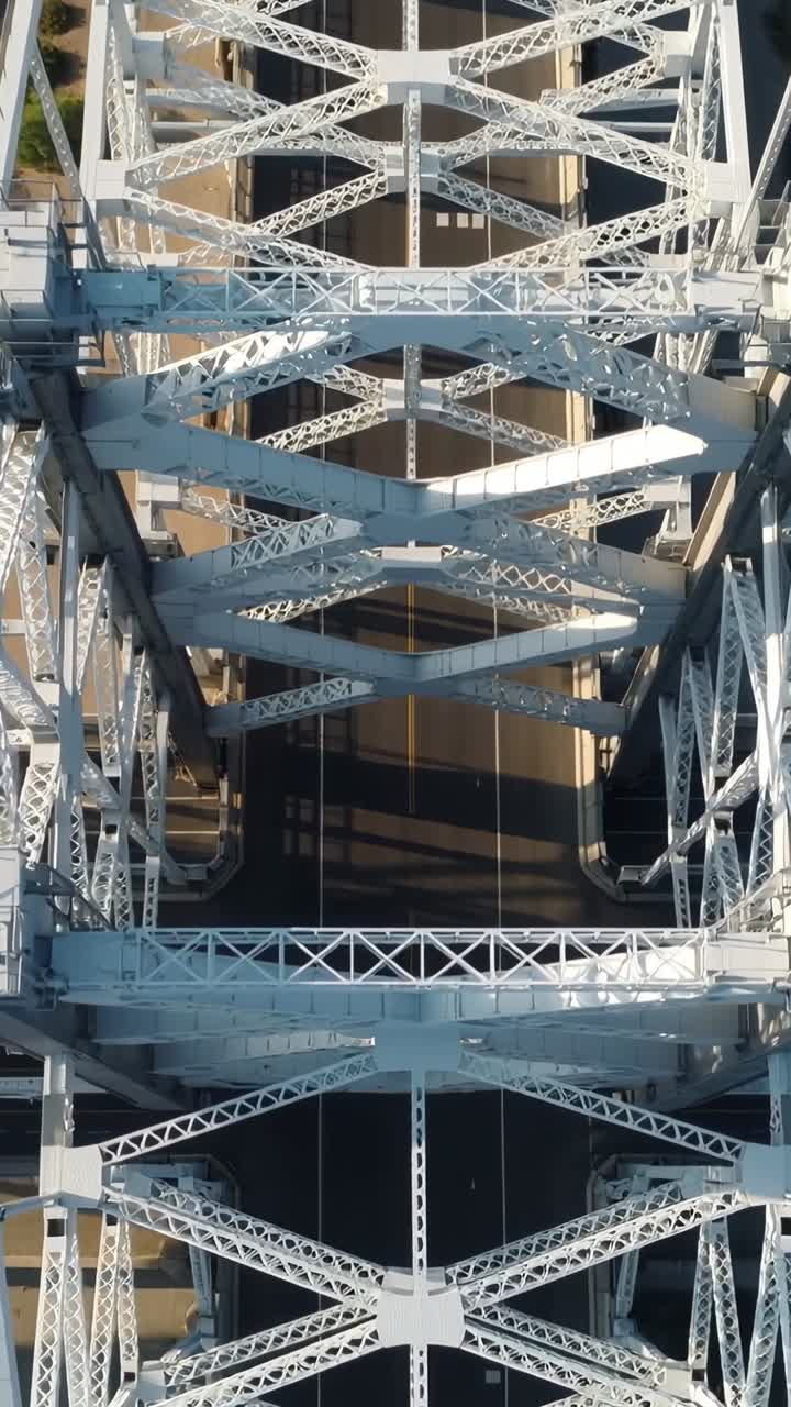 Vertical video: Starting drone gliding along truss bridge, revealing empty road showing pattern