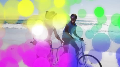 colorful bokeh animation over people walking bicycles on beach