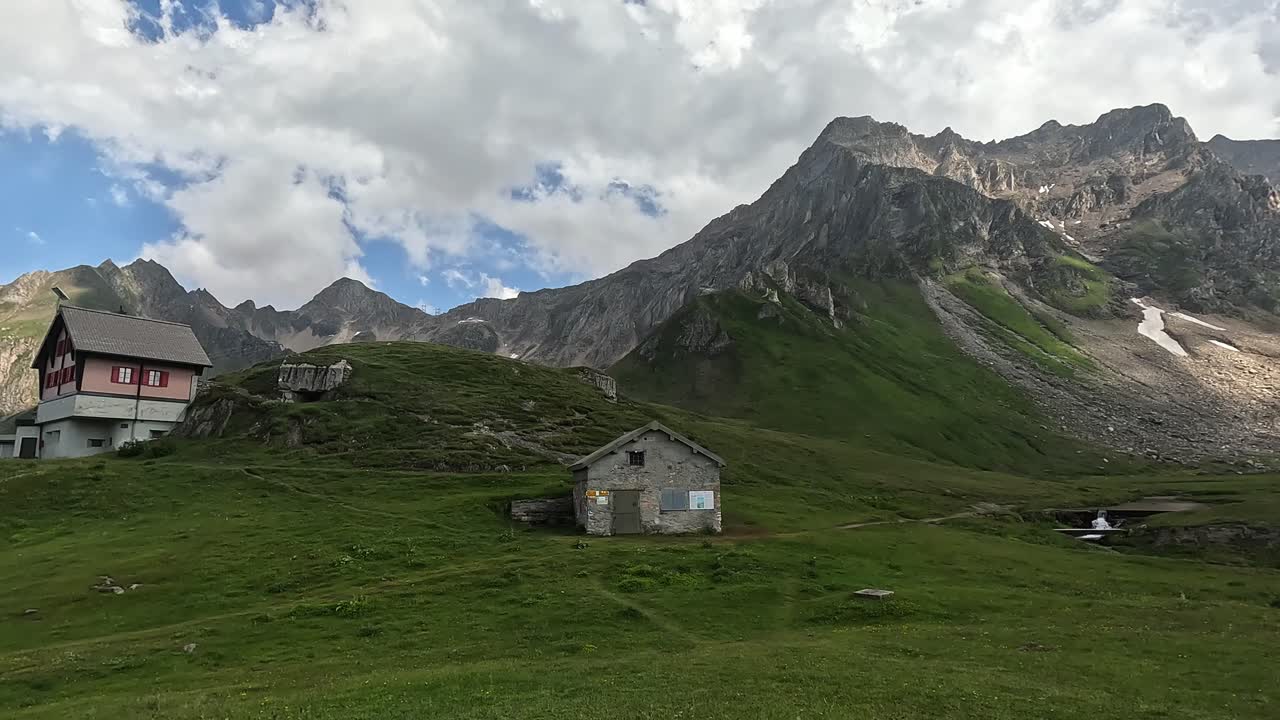 Vista su una splendida valle di montagna con baite e imponenti montagne circostanti