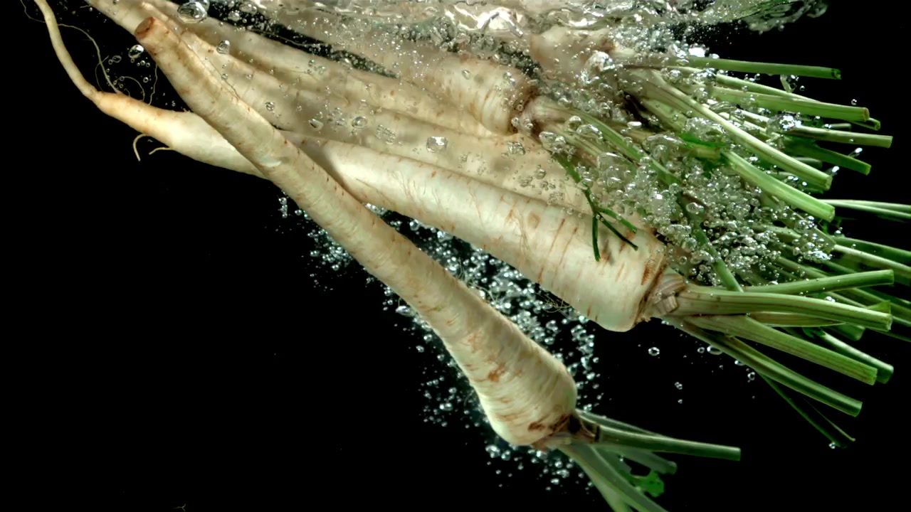 Slow motion van vallende verse pastinaken in water