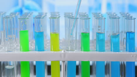 Lab-assistant-adding-green-liquid-in-test-tube-monitoring-chemical-reaction.-Technician-carefully-drips-the-solution-from-the-pipette-into-glass-tubes-for-DNA-analysis.-Pharmaceutics-Laboratory.-High-quality-4k-footage