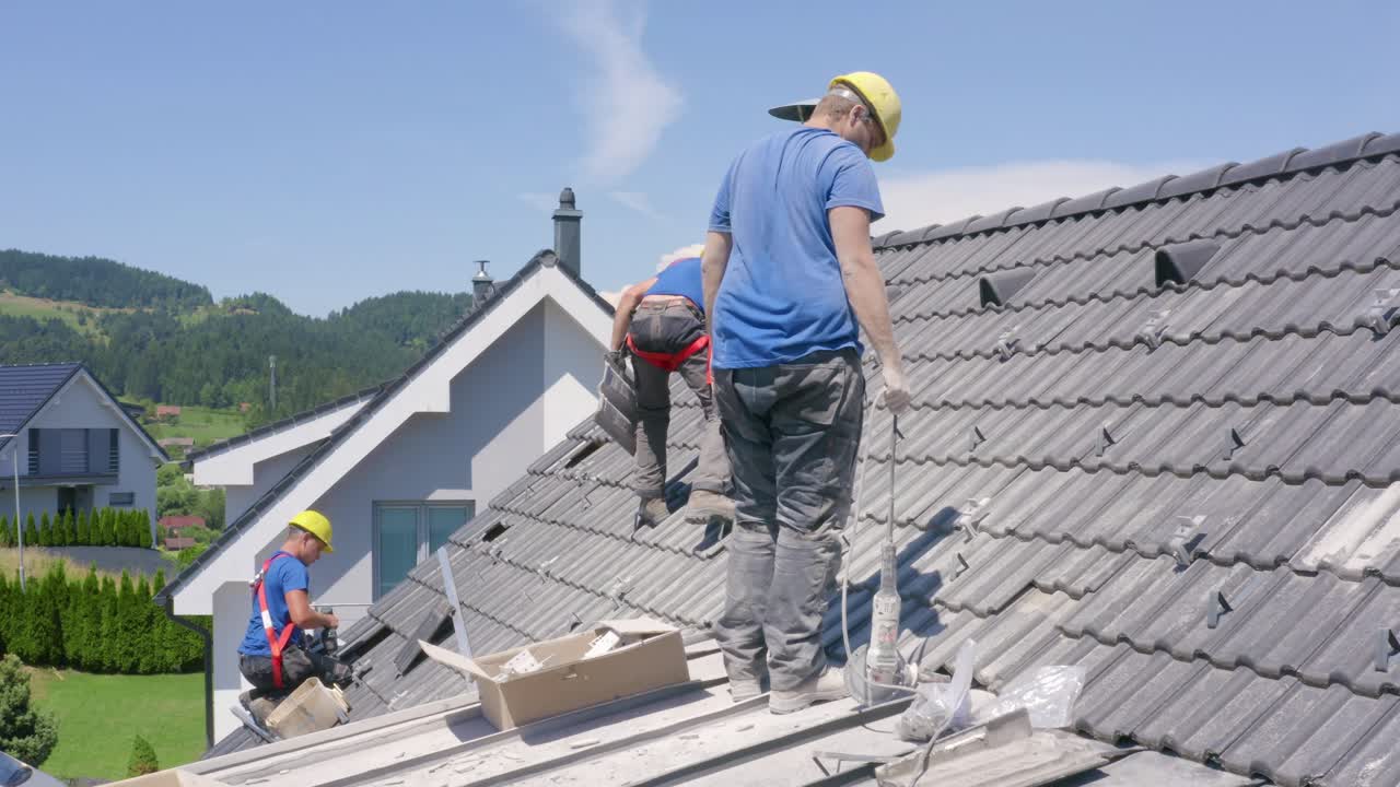 Dust flies around roofers cutting material for solar panel installation