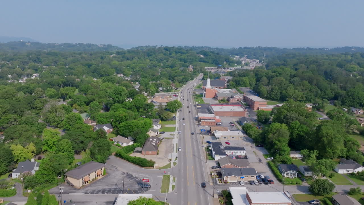 An aerial view of Brainerd Road in Chattanooga, TN, shows a long, straight stretch lined with small businesses, houses, and a prominent church steeple.