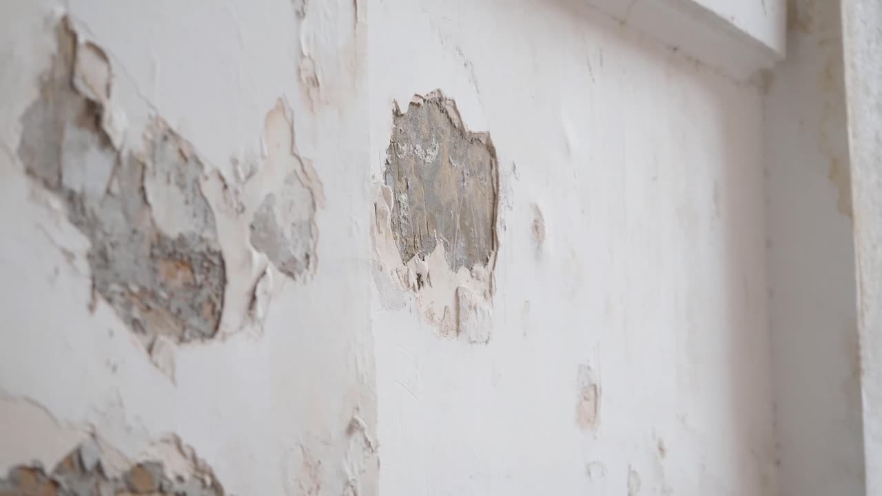 Close-up of Peeling Paint and Damaged Plaster on an Old Wall