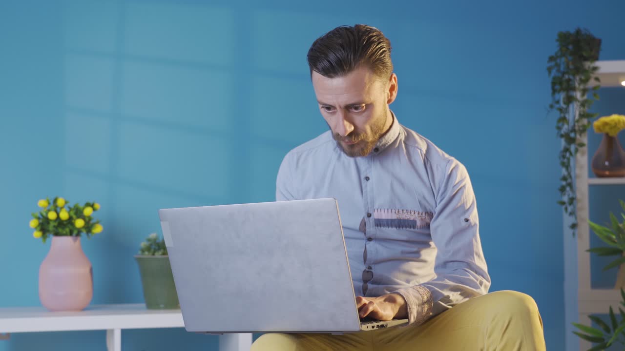 un joven adulto elegante y carismático que usa una computadora portátil en casa.
