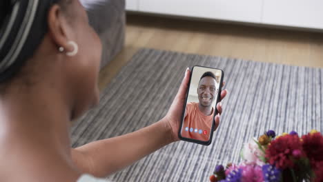 biracial woman holding smartphone with african american man on screen