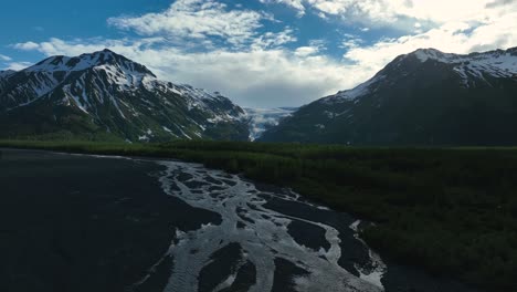 volando sobre el río trenzado con una cordillera rocosa al fondo en alaska, ee.uu.