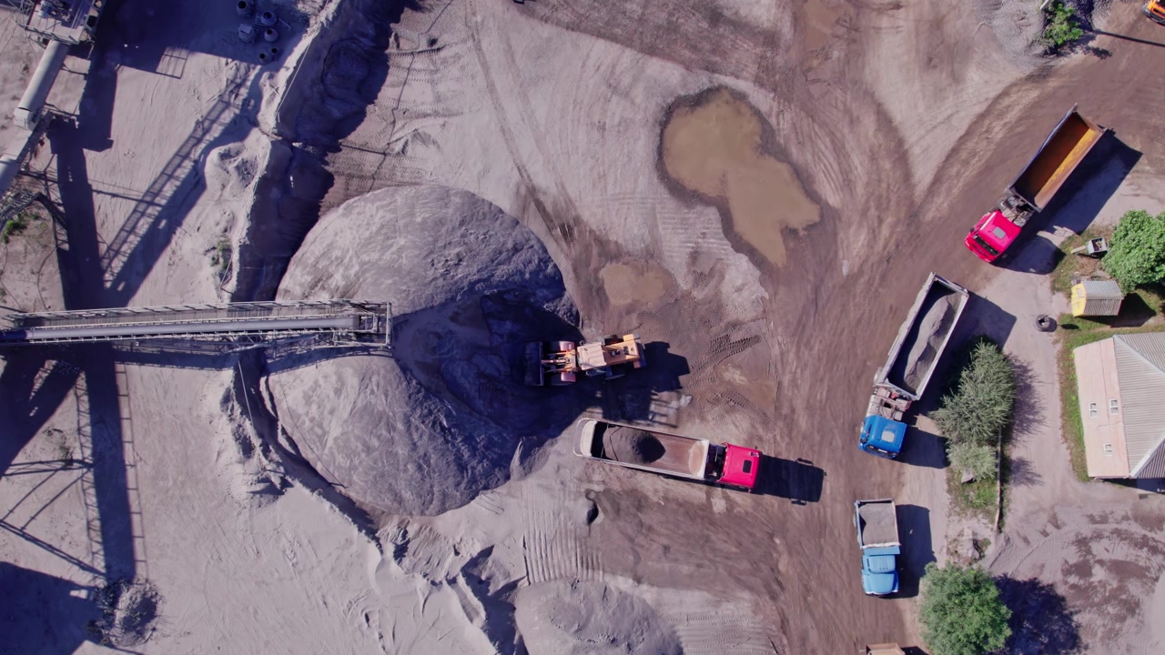 Quarry site shows machinery and trucks moving materials