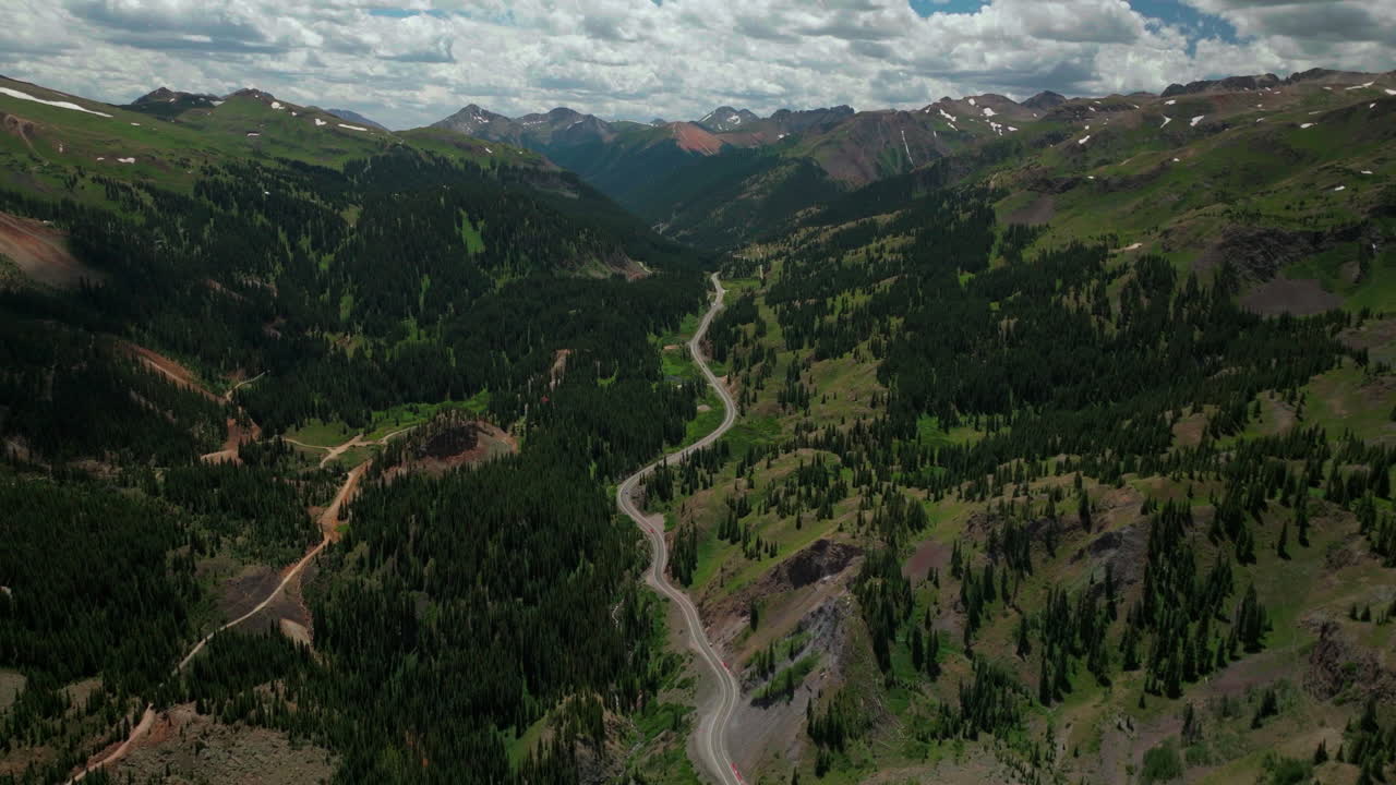 drone cinematográfico aéreo verano autopista de un millón de dólares paso de montaña roja silverton ouray telluride tarde verde exuberante flores silvestres carretera de automóviles de viento de alta altitud vista panorámica 14er hacia adelante para revelar