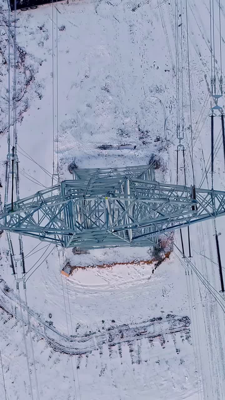 Top view of a high-voltage pylon in the snow. Drone shot.