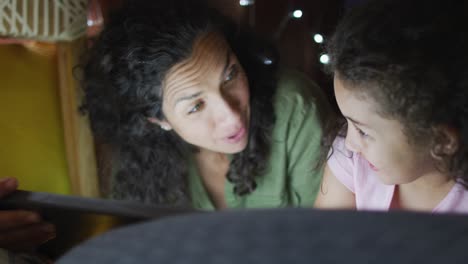 madre e hija de raza mixta usando una tableta en una tienda de campaña
