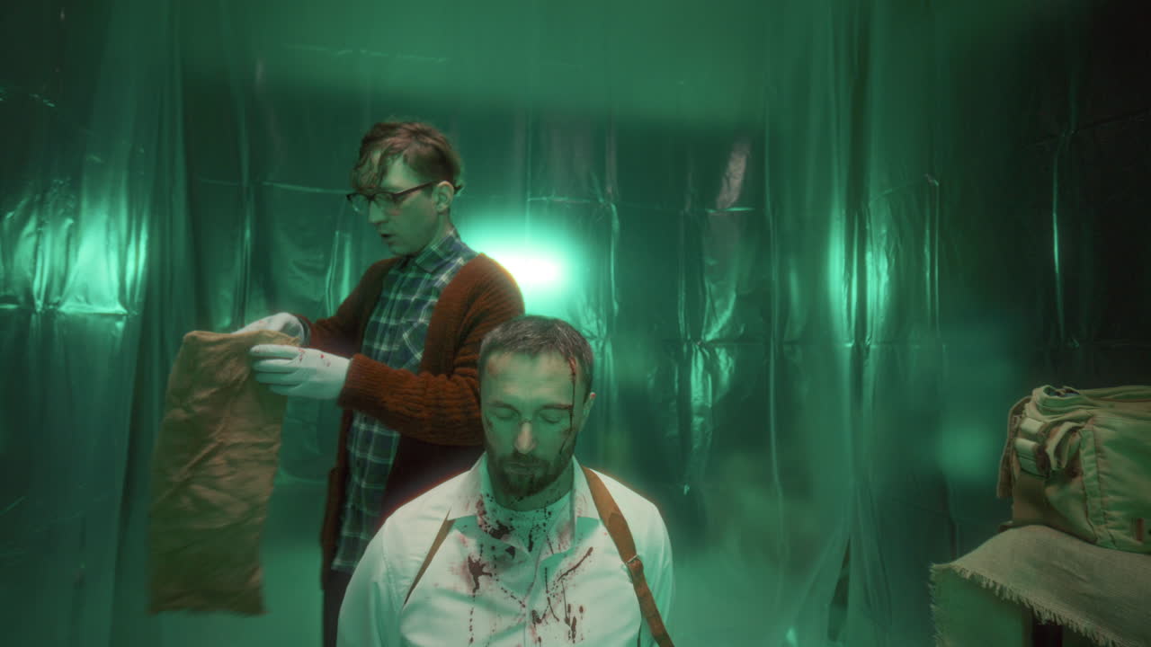 criminal con guantes quitando el saco de la cabeza de un hombre cautivo en la sala de tortura