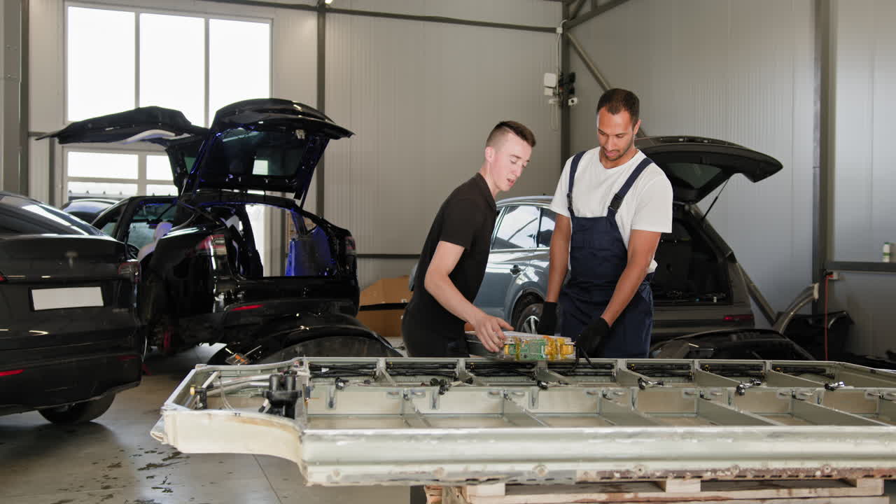 dos mecánicos trabajando en un paquete de baterías de automóviles eléctricos