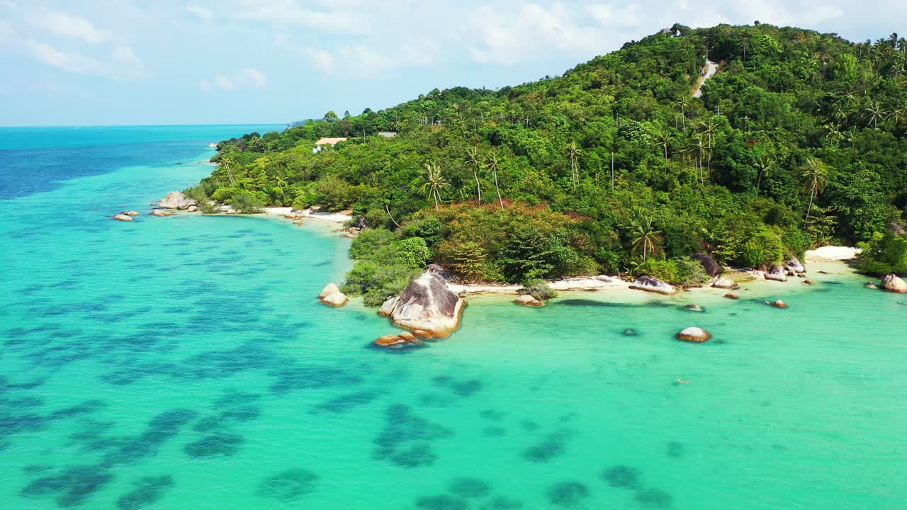 Peaceful cape of tropical island with lush vegetation, white sandy beaches and rocky coastline with cliffs washed by calm turquoise sea in Thailand