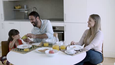 una pareja de padres y una niña desayunando juntos