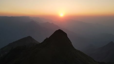 aerial drone shot of kolukkumalai range in the early morning, highlighting the peaks through the mist