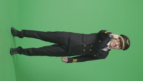 full body of asian man pilot smiling and touching his chest then pointing at you while standing in the green screen background studio