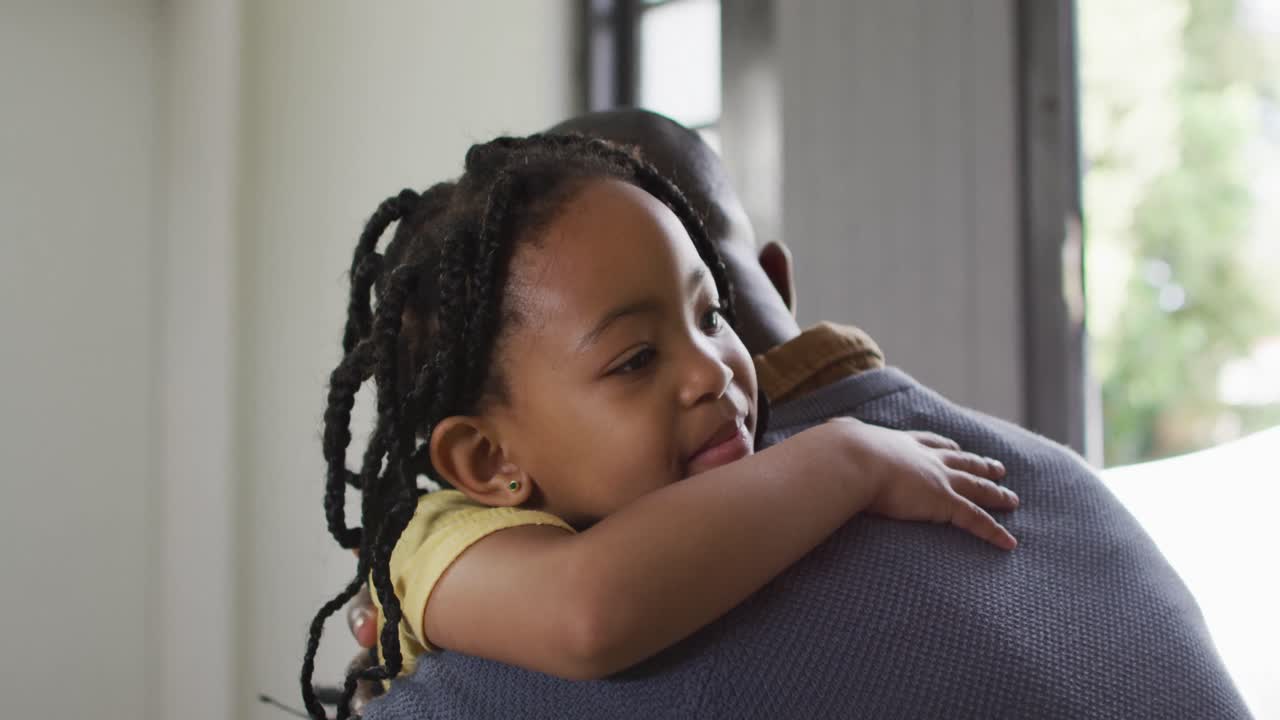 feliz hija afroamericana y padre abrazándose en el sofá