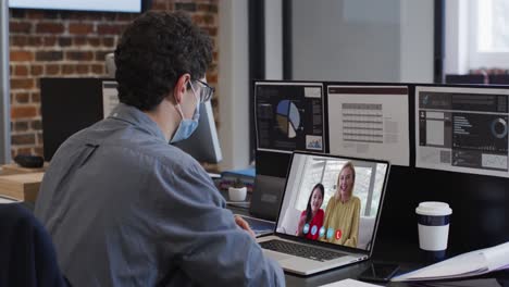 Caucasian-man-on-laptop-video-chat-wearing-face-mask-in-office