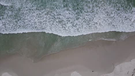 Escena-Tranquila-Con-Olas-Del-Mar-Bañando-Una-Playa-De-Arena-Desde-Arriba