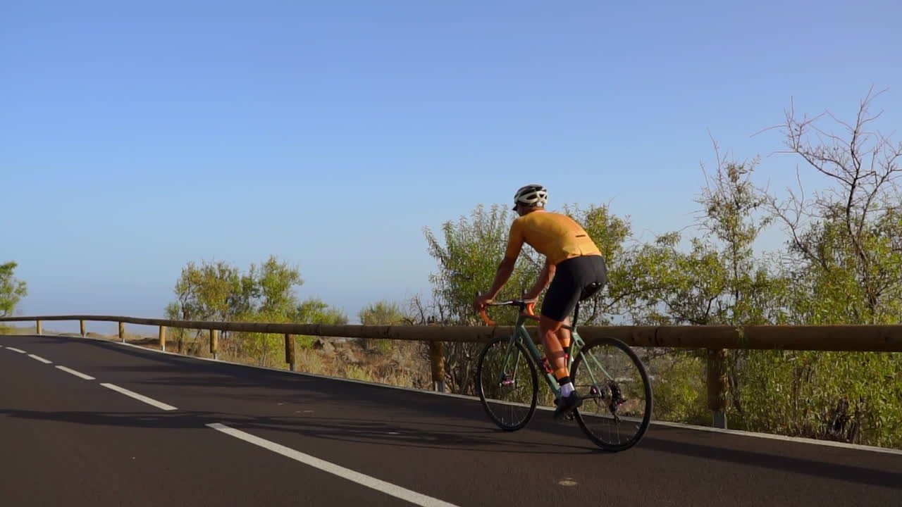 Amid the tranquility of the morning, a man takes his road bike for a spin on a deserted road, immersing himself in outdoor exercise. The slow-motion capture accentuates the essence of extreme sports