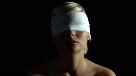 crying blind folded woman with tears on her chin over black background