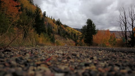 El-Lado-A-Nivel-Del-Suelo-De-La-Carretera-Se-Acerca-A-Los-Colores-De-Otoño-Con-Los-Faros-Encendidos