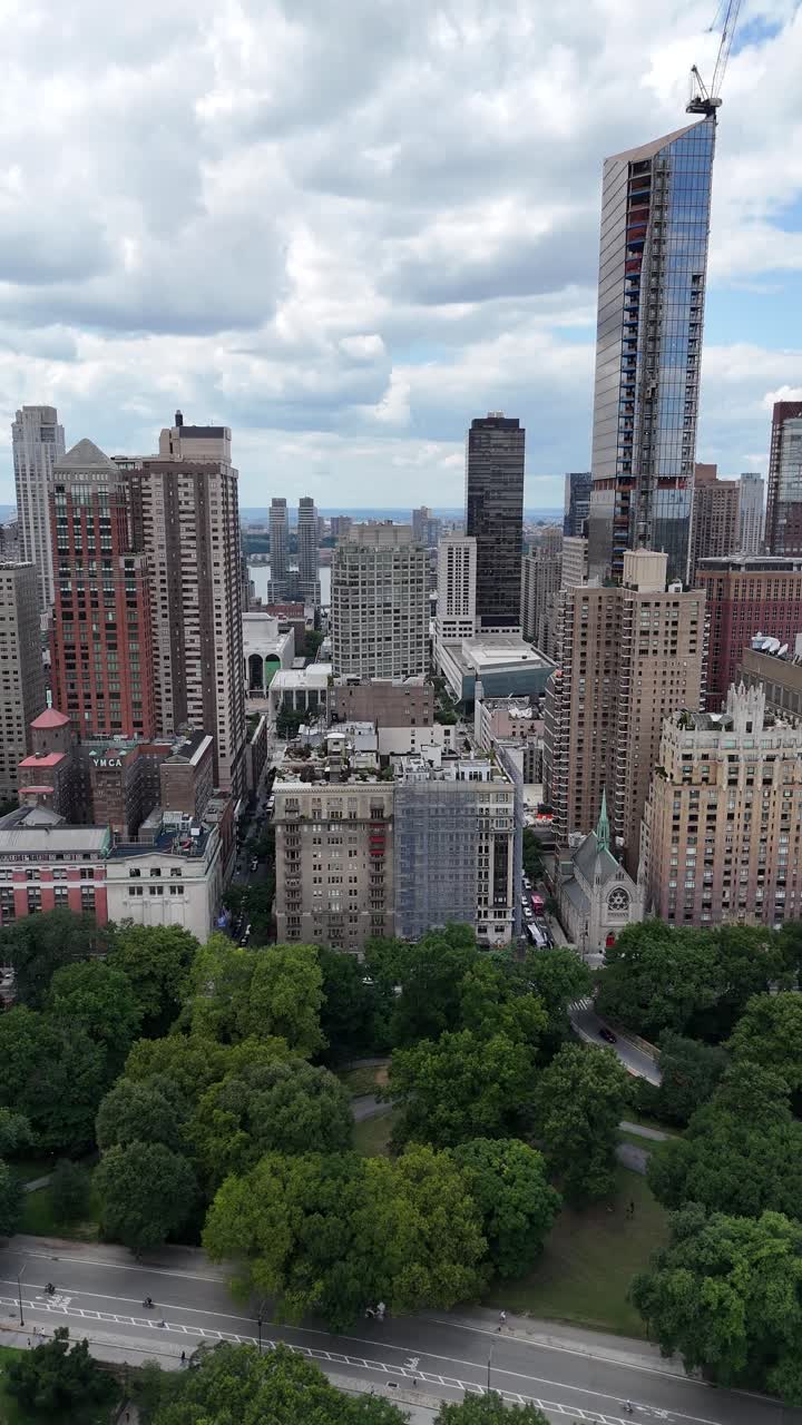 Vertical Pan drone shot of Upper West Side NYC with Central Park in the foreground, showcasing the contrast between urban skyline and green space.