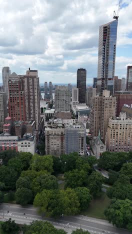 vertical pan drone shot of upper west side nyc with central park in the foreground, showcasing the contrast between urban skyline and green space.