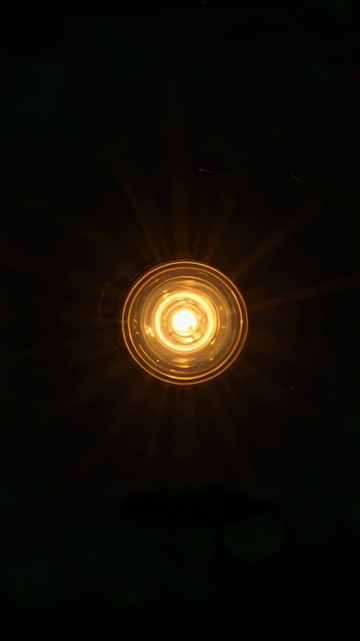 Video verticale: Lampada da soffitto che emette un bagliore caldo per un design che inizia luminoso e mostra anelli sottili.