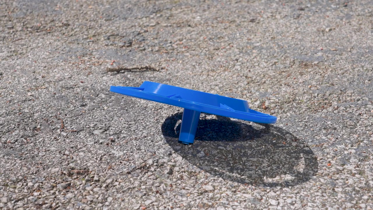 A blue plastic bird feeder lays busted on the cement.