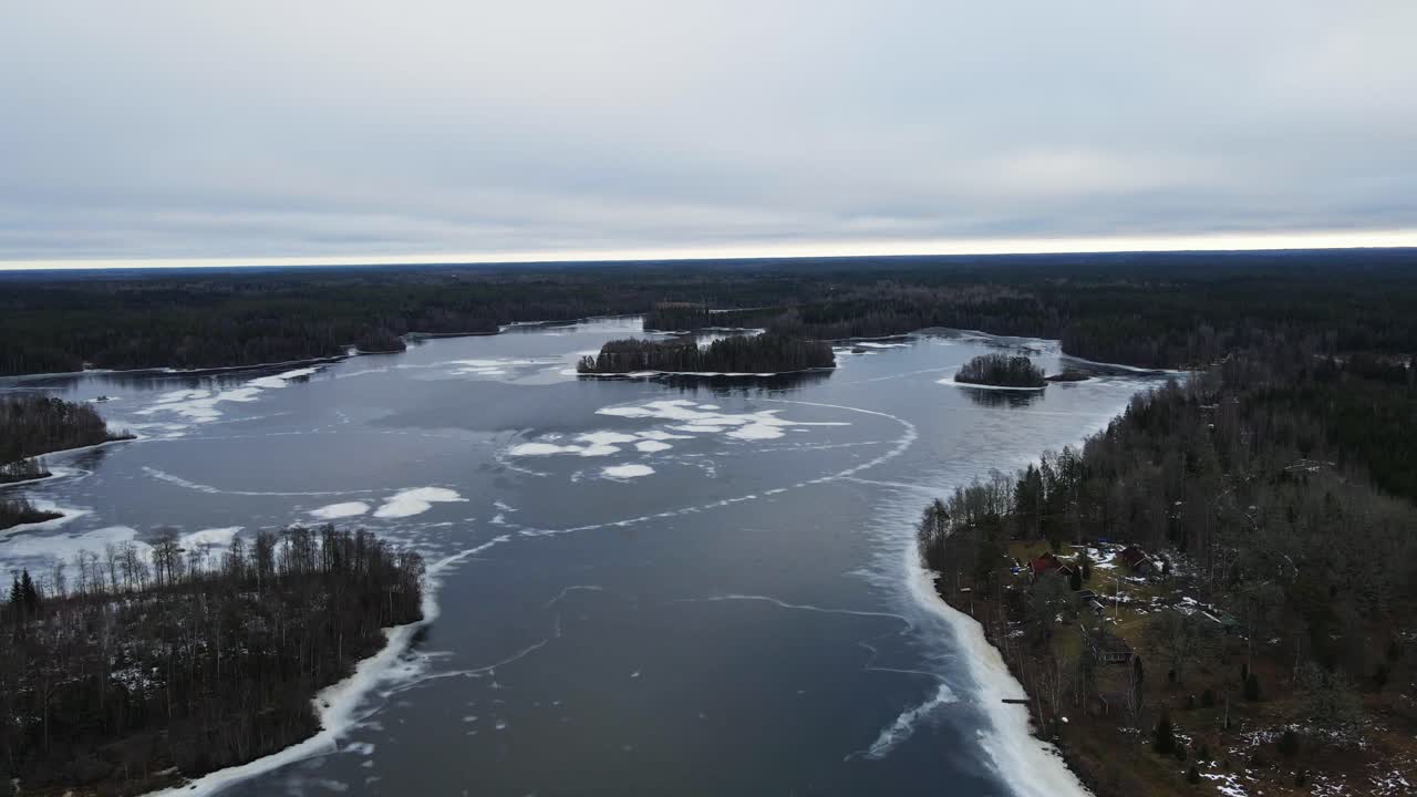 Ilmakuva kauniista jäätyneestä järvestä suuren metsän keskellä Ruotsin maaseudulla pilvisenä päivänä