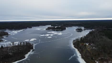 aerial of a beautiful frozen lake in the middle of a large forest in rural sweden on an overcast day