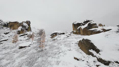 witness breathtaking winter beauty as a drone captures stunning views of snow-covered cliffs and rocky formations in a serene mountainous region during cold weather.