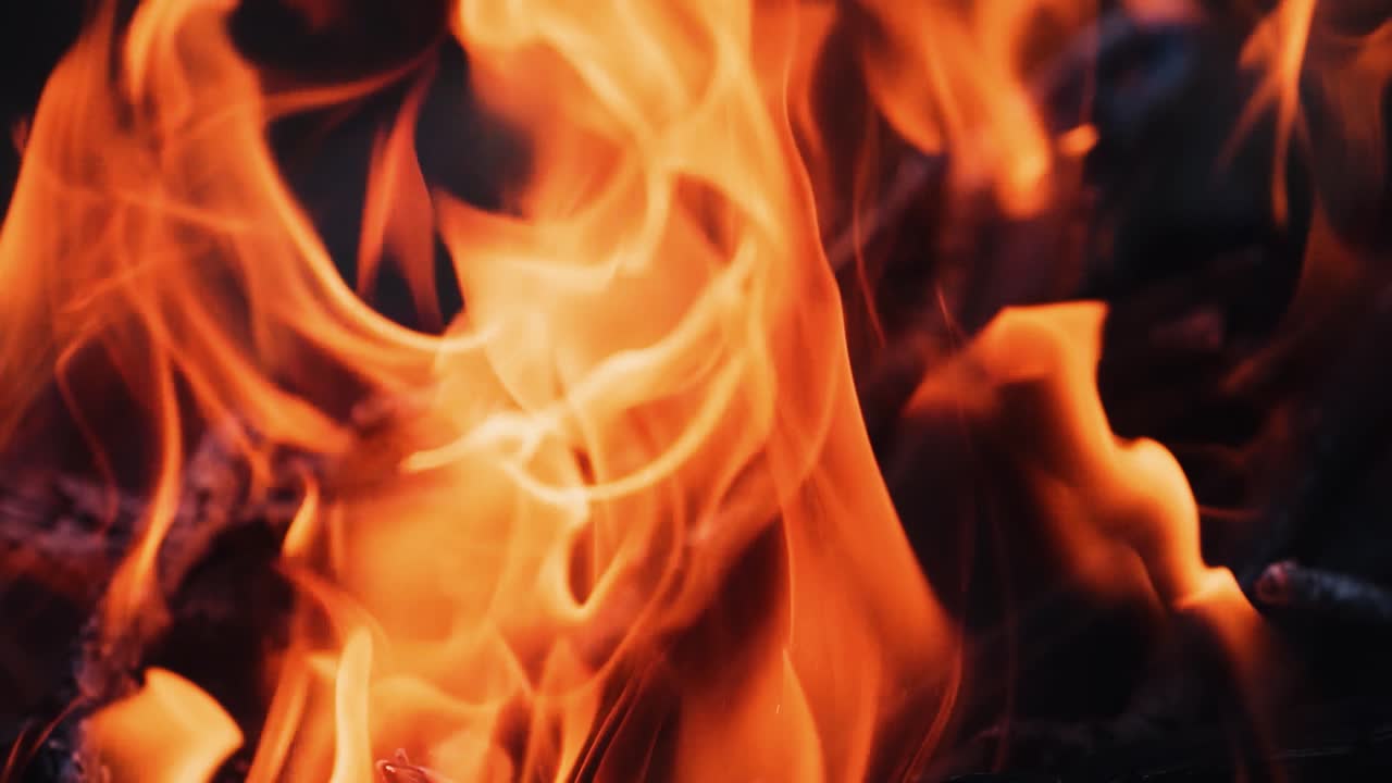Slow motion of fire flame. Beautiful fire burns brightly. Burning logs in orange flame. Close-up.
