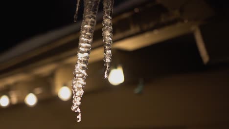 Hintergrundbeleuchteter,-Schmelzender-Eiszapfen,-Der-Vom-Dach-Hängt-Und-In-Zeitlupe-Tropft