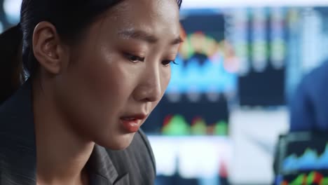 focused professional analyzing financial data on dual monitors with charts and graphs in a modern office environment