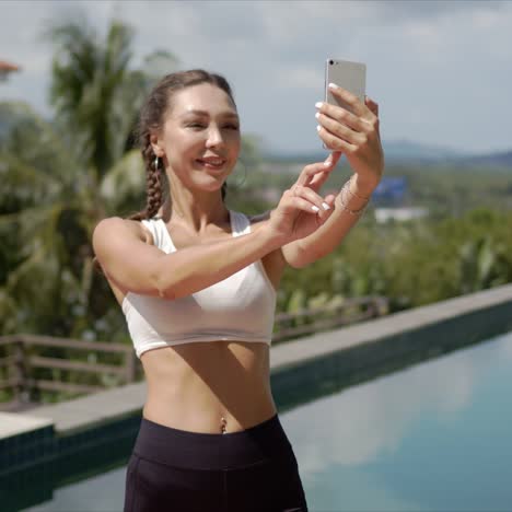 cheerful sportswoman taking selfie on poolside