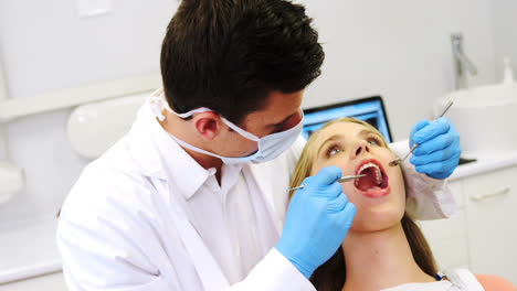 dentist examining a female patient with tools