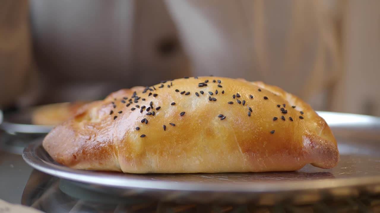 Hand Picking Up Freshly Baked Pastry with Sesame Seeds