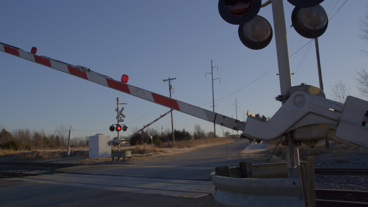 Flashing red lights at railroad crossing while train approaches in rural Texas countryside