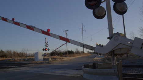 flashing red lights at railroad crossing while train approaches in rural texas countryside