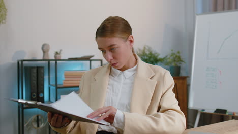 business woman at home office analysing paperwork documents, shocked by sudden victory good news wow